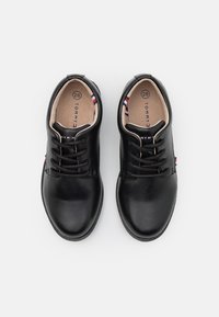 Czarne skórzane buty z zaokrąglonym noskiem, sznurowanym zapięciem, beżowym wnętrzem i subtelnym detalem marki. Rozmiar oznaczony jako 28.