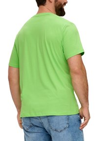 Groen katoenen T-shirt met korte mouwen, ronde hals, zachte textuur en een getailleerde snit, gecombineerd met lichtblauwe denim jeans.