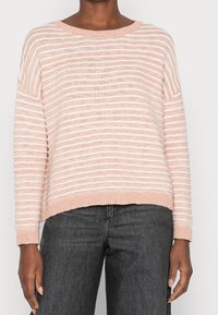 Jasnoróżowy sweter w paski, wykonany z fakturowanej dzianiny. Posiada szeroki dekolt i ściągacz na dole, z kontrastującymi białymi paskami.