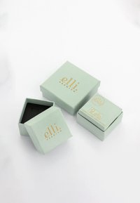 Mintgrønne gaveæsker med guldtekst, der inkluderer en større firkantet æske og en mindre rektangulær æske, alle med en mat overflade.