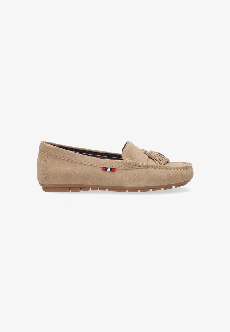 Beige suede loafer with a decorative tassel, rounded toe, and stitched detailing. Features a rubber sole and a small logo with red, white, and blue accents.