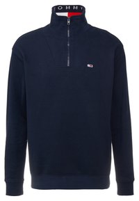 Pullover in pile blu navy con colletto alto e zip a metà, caratterizzato da un collo a coste con marchio e un logo discreto sul petto.