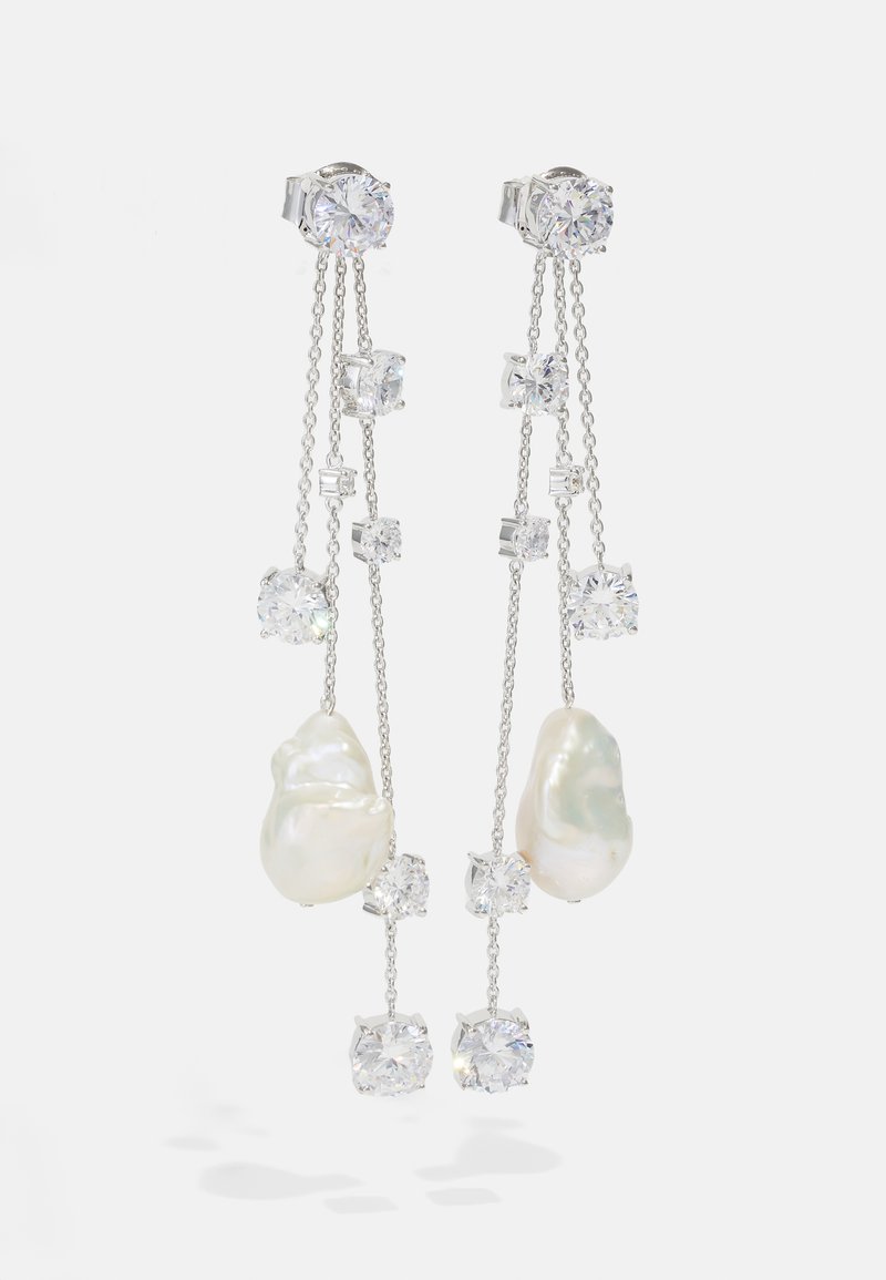 Ασημένια σκουλαρίκια με σταγόνες που διαθέτουν ανώμαλα λευκά μαργαριτάρια, καθαρούς ζιρκόνους και λεπτές αλυσίδες διαφόρων μηκών.
