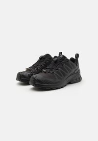 Black athletic shoes made of mesh and synthetic material. Features a textured upper, elastic laces, and a rugged rubber sole with patterned treads.
