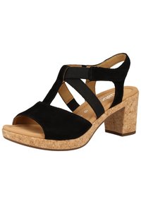 Sandale en daim noir avec talon compensé en liège, dotée de brides élastiques croisées et d'un design à bout ouvert. Semelle intérieure lisse pour le confort.