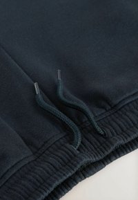 Mørkeblå bomulds sweatpants med ribbet talje og to flettede snørebånd. Blød tekstur, minimale syninger og ingen synlige mønstre.