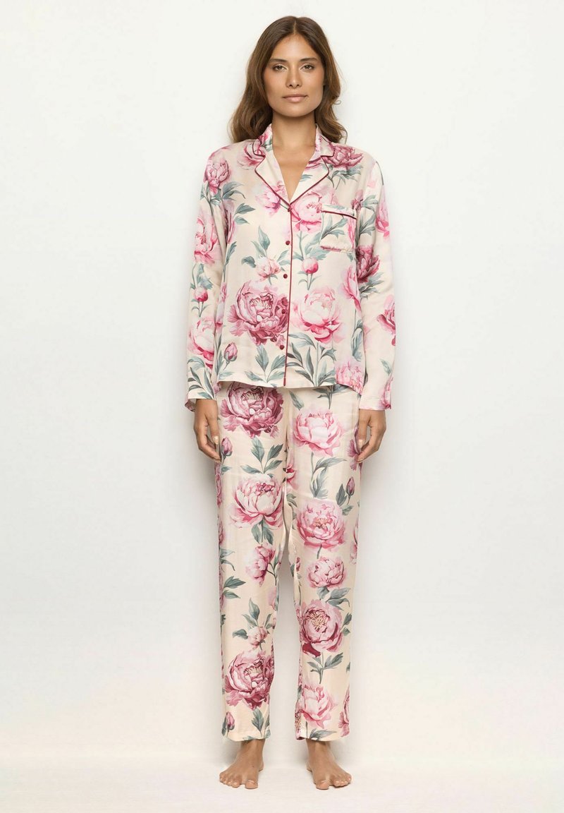 Set de pijama din material moale cu un imprimeu mare de bujori roz pe un fundal bej, incluzând o cămașă cu nasturi și pantaloni asortați.