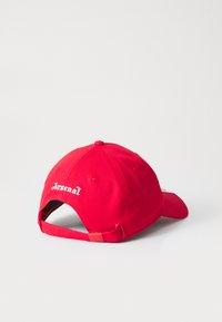 Červená baseballová čiapka s vyšitým logom "Arsenal" v bielej farbe. Obsahuje zakrivený šilt a nastaviteľný pásik vzadu.