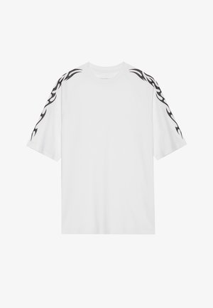 T-shirt en coton blanc à manches courtes. Présente des motifs de flammes noires le long des épaules. Design classique à col rond. Texture lisse.