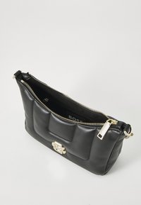 Sac à main en cuir noir avec texture matelassée, quincaillerie dorée, fermeture éclair et détail de logo. Ouvert, montrant l'intérieur et la doublure.