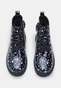 Botas de tobillo negras de charol con un acabado texturizado, que presentan un patrón de corazones multicolores. Diseño con cordones y un asa en el talón.