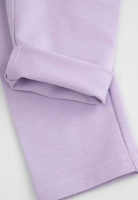 Liliowa bawełniana tkanina o gładkiej fakturze, z podwiniętym brzegiem i subtelnym prążkowaniem, prezentująca proste, czyste linie.