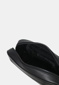 Borsetta in pelle nera con superficie testurizzata, dotata di chiusura con zip superiore e tasca interna. Design compatto e snello.