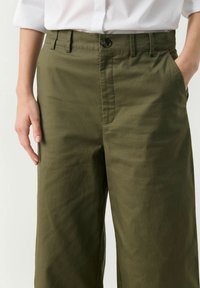 Olijfgroene broek van katoen met een rechte pasvorm, voorzien van een knoopsluiting, zijzakken en een gladde textuur.