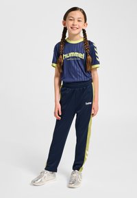 Granatowy sportowy strój z limonkowymi akcentami, składający się z krótkiego topu z krótkim rękawem i dopasowanych spodni. Całość uzupełniają srebrne trampki.