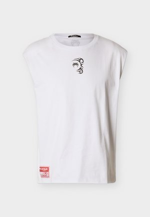 Tricou alb fără mâneci din bumbac, cu un mic design grafic negru pe piept și o etichetă roșie cu brand în partea de jos.