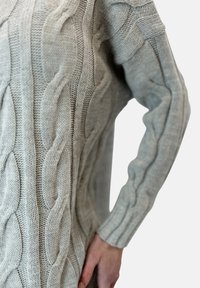 Ljust grått stickat tröja med kablar, texturerade �ärmar och ribbad manschett. Passformen är lös och avslappnad.