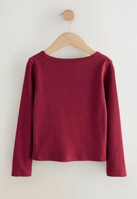 Top z dolgimi rokavi iz bordo rebraste tkanine. Ima okrogel izrez in raven spodnji rob, prikazan na lesenem obešalniku na svetlem ozadju.