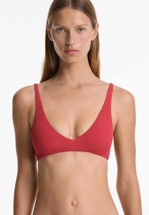 Rode gebreide bikinitop met een diepe V-hals, dunne bandjes en een gestructureerde stof. Eenvoudig ontwerp benadrukt een natuurlijke silhouet.