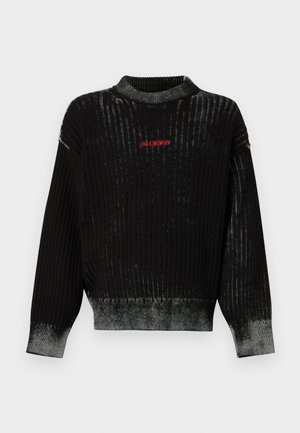Suéter de punto acanalado negro con cuello redondo, que presenta un dobladillo en degradado gris y detalles de texto en rojo. Textura suave y ajuste holgado.