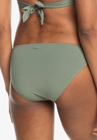 Gröna bikiniunderdelar med en slät yta, mid-rise design och en liten logotagg. Knytning bak ger en detalj till det övergripande utseendet.