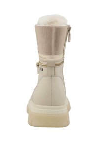 Bežová bota s ribbed látkovým svrškem a měkkým umělým kožešinovým podšívkou. Obsahuje boční zip a strukturovanou, chunky bílou podrážku.