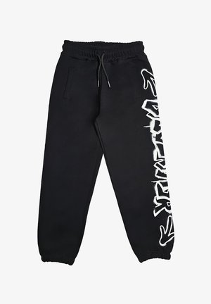 Pantaloni jogger neri con vita ed orli elasticizzati, tasche laterali e design testuale in stile graffiti bianco sulla gamba destra.