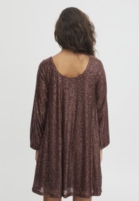 Robe à sequins en bourgogne profond avec une coupe ample, décolleté dos arrondi et manches trois-quarts. Surface texturée composée de sequins.