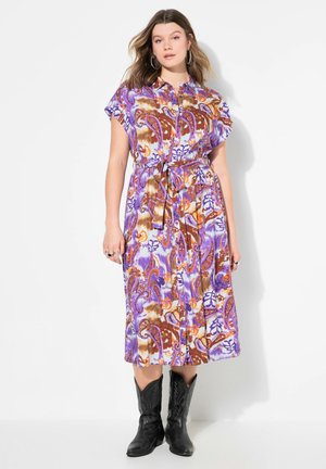 Vestido de estampado paisley púrpura con mangas cortas, cintura ceñida y cinturón de lazo; combinado con botas de vaquero negras. Textura de tela suave.