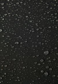 Wodoodporny czarny materiał z licznymi przezroczystymi kroplami wody, podkreślający gładką fakturę i gęsto tkany powierzchnię.