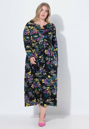 Vestido maxi floral en negro con mangas largas, que presenta flores y hojas de colores. Detalles en V y diseño con pliegues.