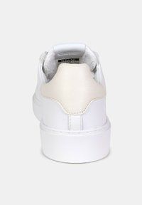 Sneaker bianca in pelle con una texture liscia, forma arrotondata e un accento sul tallone beige a contrasto. Design minimalista senza marchio visibile.