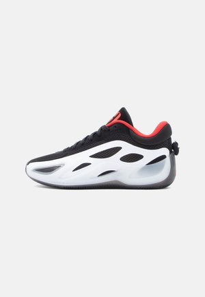 Black and white sneakers with red accents. Mesh upper, streamlined design, and distinctive cutouts for ventilation. Rubber sole.