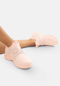 Rosa Netzsneaker mit Kreuzriemen und strukturierten Sohlen, entworfen für Atmungsaktivität und Komfort. Leichte und flexible Bauweise.