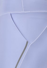 Ljuslila idrottstyg med ett geometriskt mönster. Har platta sömmar och en kontrasterande grå detalj. Slät textur.