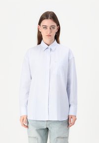 Lyseblå stripete skjorte med knapper, krage, lange ermer og brystlomme. Stoffet ser glatt ut med en avslappet passform.