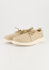 Beige Stoffschuhe mit strukturierter Oberfläche, runder Zehenpartie und Schnürdesign. Verfügt über Gummisohlen in heller Farbe und minimalen Nähten.