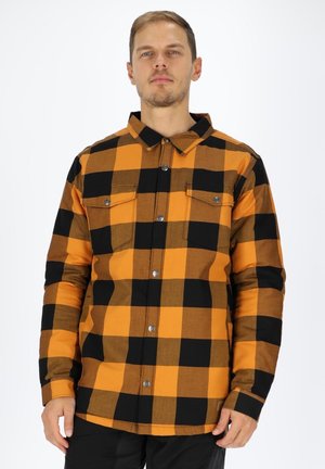 Oranje en zwarte geruite overhemd met knoopsluiting aan de voorkant, twee borstzakken met metalen accenten en lange mouwen. De stof lijkt gestructureerd.