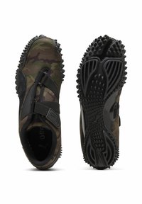 Αθλητικά παπούτσια με καμουφλάζ σχέδιο και μαύρες καουτσούκ σόλες που διαθέτουν καρφιά και ρυθμιζόμενους ιμάντες στο πάνω μέρος.