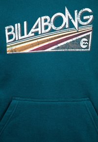 Felpa color teal con tasca a marsupio frontale, caratterizzata da un logo grafico consumato che include strisce in giallo, arancione e bordeaux.