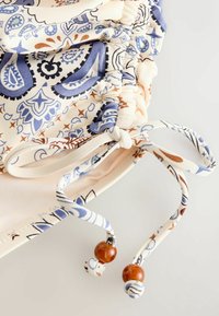 Tissu avec motifs cachemire bleu et marron, bordures élastiquées froncées et cordons noués avec perles marron sur fond clair.