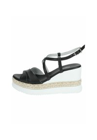 Sandalias de cuña de cuero negro con tiras cruzadas. Presentan una plataforma blanca con una capa de yute texturizado y tejido, y tachuelas doradas. Correa de tobillo ajustable.