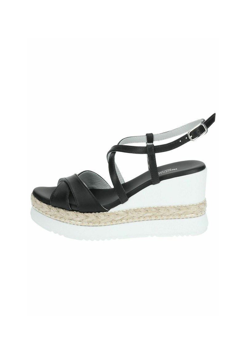 Sandalias de cuña de cuero negro con tiras cruzadas. Presentan una plataforma blanca con una capa de yute texturizado y tejido, y tachuelas doradas. Correa de tobillo ajustable.