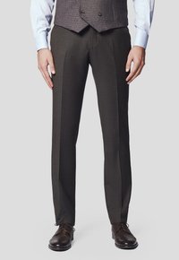 Dopasowane ciemnoczekoladowe spodnie z gładkiego, strukturalnego materiału o prostym kroju, w połączeniu z brązowymi eleganckimi butami i szarym kamizelką.