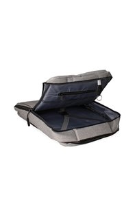 Grijze stoffen rugzak met een ritssluiting. De binnenkant heeft een marineblauwe voering, vakken en verstelbare schouderbanden voor organisatie.