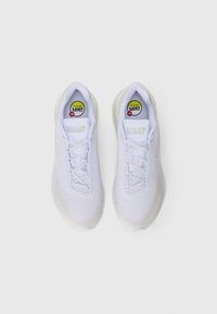 Une paire de chaussures de course Nike Air Max blanches vue de dessus sur un fond blanc, montrant la texture en maille et les lacets.