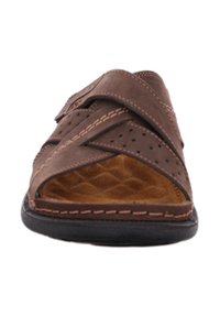 Sandale en cuir marron avec des brides croisées, un design perforé et une semelle intérieure beige matelassée. Présente des coutures contrastantes et une semelle en caoutchouc noire.