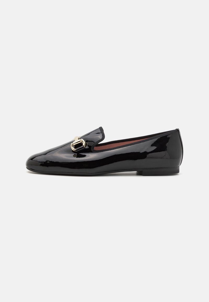 Mocassin plat en cuir verni noir avec détail de boucle métallique dorée, petit talon et bout rond sur un fond clair uni.