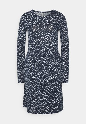 Vestido azul-marinho com mangas longas, apresentando um padrão abstrato branco. A cintura ajustada flui para uma saia ligeiramente evasê. Textura suave.