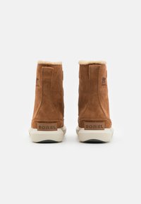 Botines de ante marrón con un suave cuello de piel, cuentan con una suela de goma y un logotipo en relieve en el talón y en el lateral.